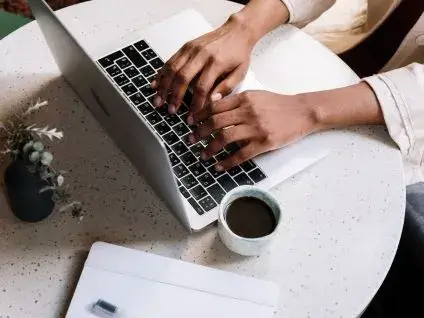 Młoda, uśmiechnięta osoba szybko pracująca na laptopie lub tablecie, symbolizująca efektywne naprawianie błędów w sklepie online i oszczędność czasu.